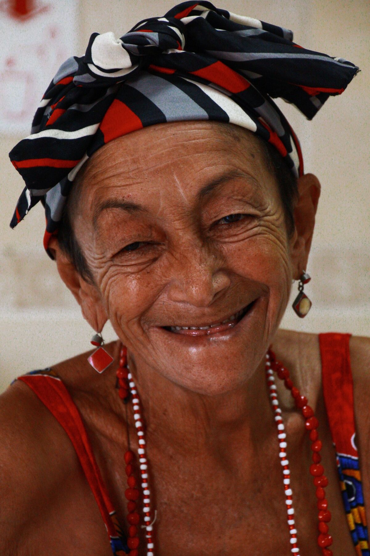 Artesã idosa sorrindo, com lenço estampado na cabeça