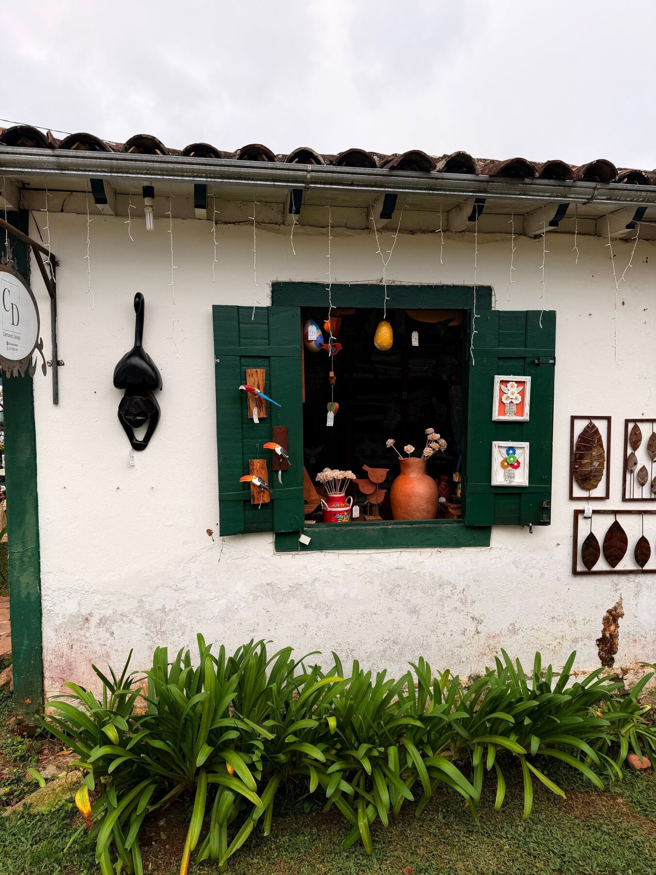 Janela de ateliê com venezianas verdes e peças artesanais à mostra